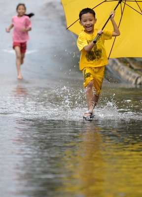 children running in the rain with yellow umbrella