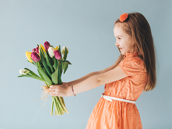 A Gift For You - Girl Holding a Bouquet of Flowers [Image © Adobe Stock]